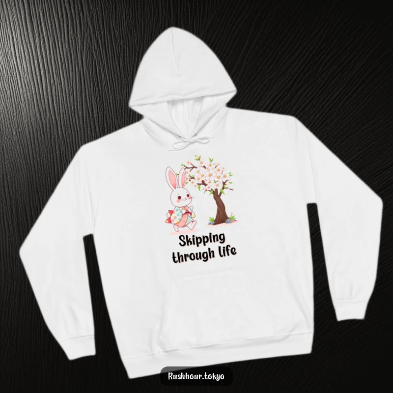 Cute kawaii bunny wearing a colorful kimono, happily skipping beside a blooming cherry tree on a cozy hoodie.