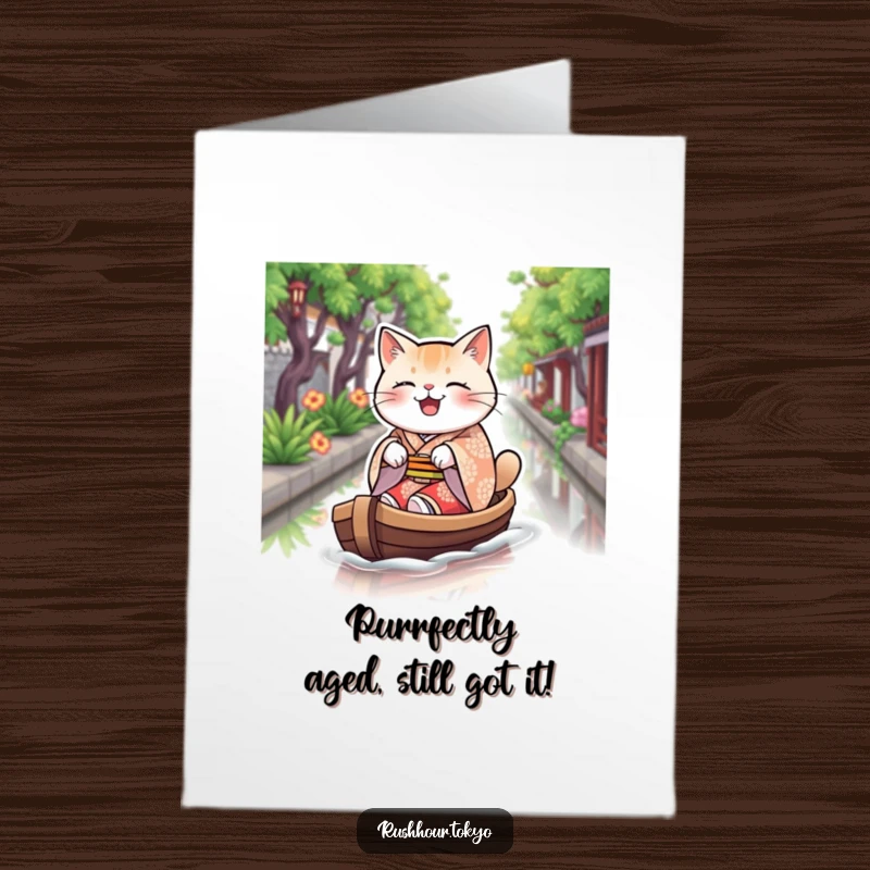 Funny Free Printable birthday card showcasing a plump cat in a patterned kimono joyfully rowing a boat on a canal.