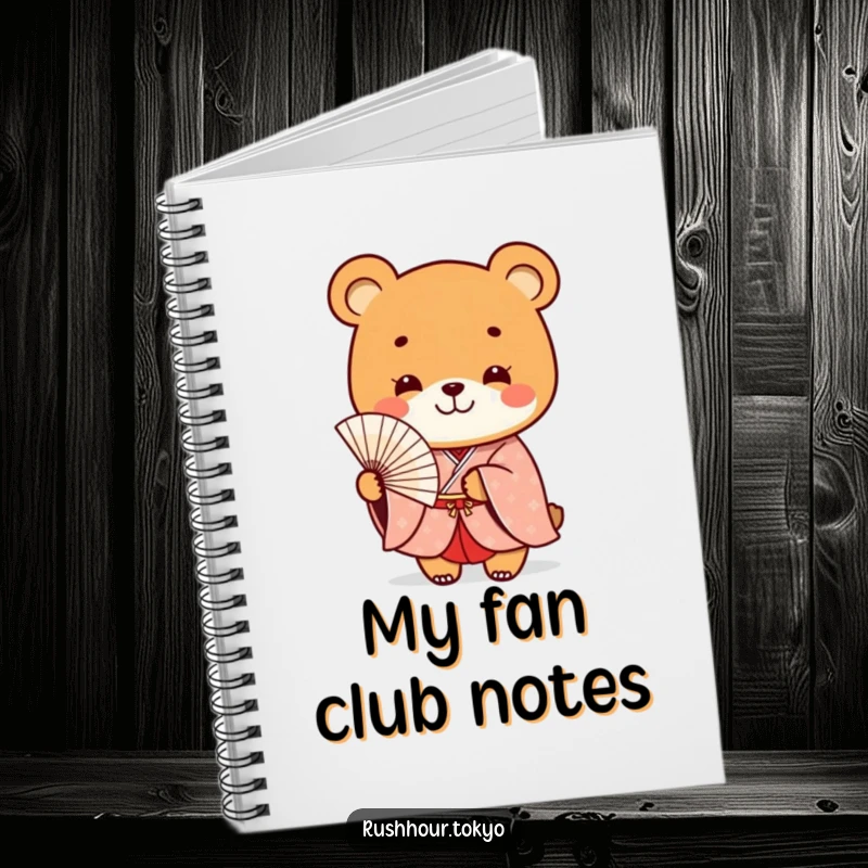 Funny playful bear character in a formal kimono smiles while holding a delicate fan, adorning the cover of this charming notebook.